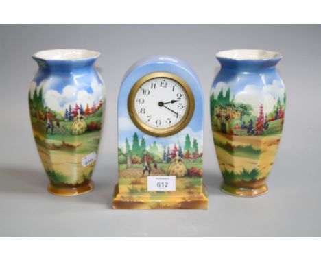 A 1930s earthenware clock garniture, the timepiece and twin vases hand coloured transfer decorated with a courting couple in 