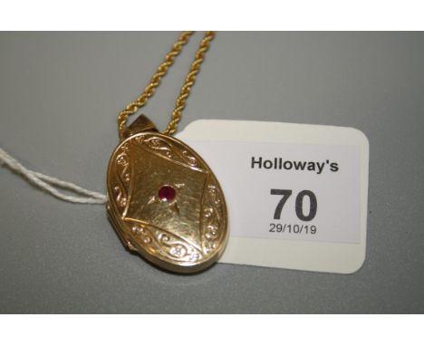 A 9ct gold and ruby locket, oval with centrally set ruby within engraved mount with associated ropetwist chain, 6.22g