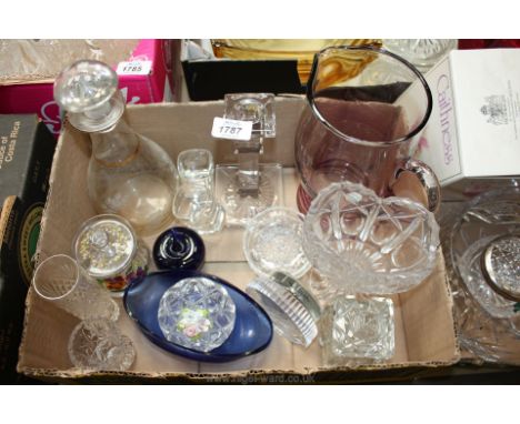 A quantity of coloured and clear glass including a water jug, decanter, blue glass apple paperweight, bud vase, trinket pot e