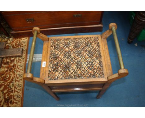 A wooden music stool with a tapestry top and brass handles.