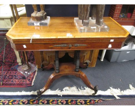 A Regency mahogany, rosewood and brass mounted card table, the canted rectangular top raised on four ring turned supports on 