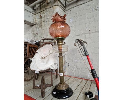 A brass and glass paraffin lamp with cranberry glass shade. 