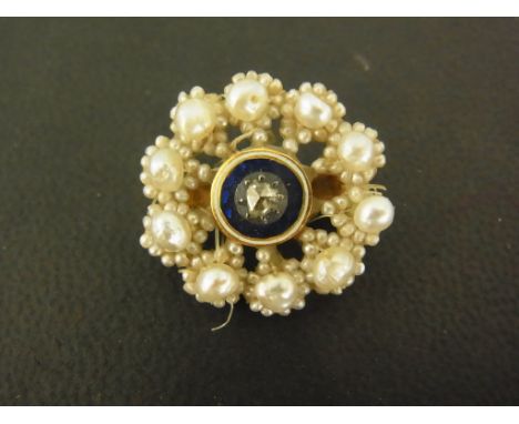 An early 20th century diamond, enamel and seed pearl brooch of snowflake design, the rose cut diamond within a blue, gold and