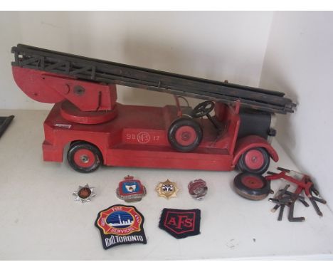 A wooden model of a 1940's fire engine in need of restoration - and six assorted badges