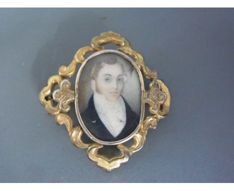 A miniature portrait of a gentleman held within a yellow metal surround presumed gold with pin to back - good condition