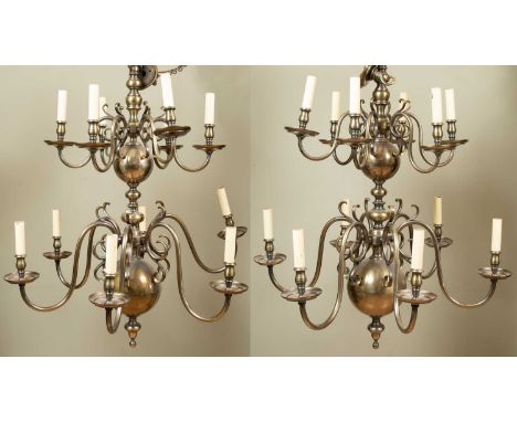 A pair of Dutch-style two-tier twelve-light brass chandeliers with scrolling branches, each approximately 90cm wide x 106cm h