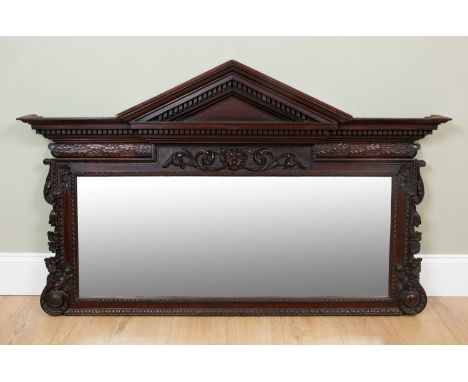 A mahogany overmantle mirror of architectural form, the frieze centrally decorated with an animal mask and with floral swags 