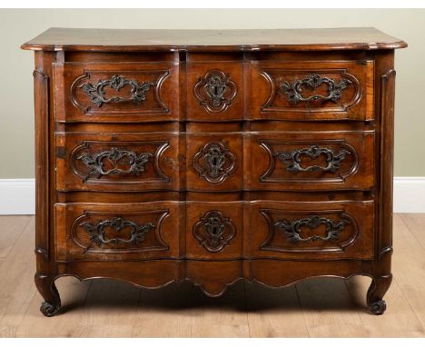 A 19th century French walnut three drawer commode with cast handles and escutcheons, and all standing on short carved scrolli