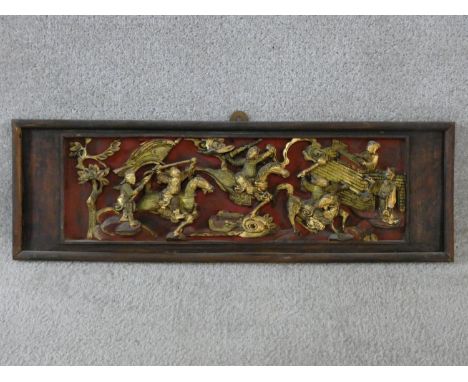 An antique Chinese carved lacquered and gilded panel with red round and warriors on horseback fighting among trees and one ma