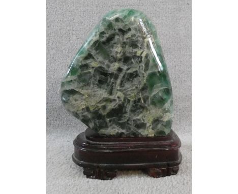 A large polished Fluorite crystal boulder mounted on a carved Chinese wooden stand. H.31cm 