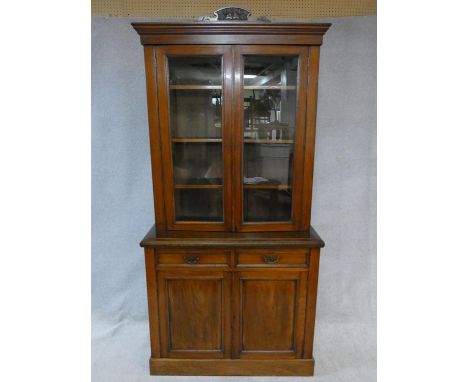 A 19th century walnut library bookcase, the upper glazed section enclosing shelves above base fitted with two frieze drawers 