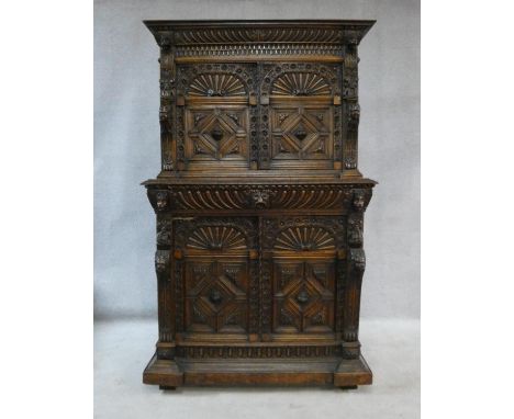 An antique oak court cupboard of compact size with carved arched panel doors with central lozenge panels above frieze drawer 