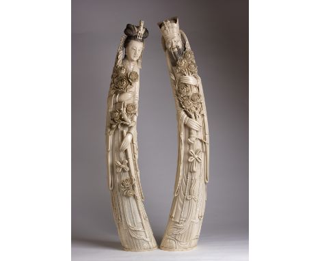 A pair of carved ivory figures of Emperor & Empress holding peonies and wearing layered robes - China, late 19th / early 20th