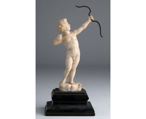 “Cupid”. A carved ivory figure depicting Cupid while shooting an arrow - France, 19th Century; ; on a wooden base. 17.7 cm, 6