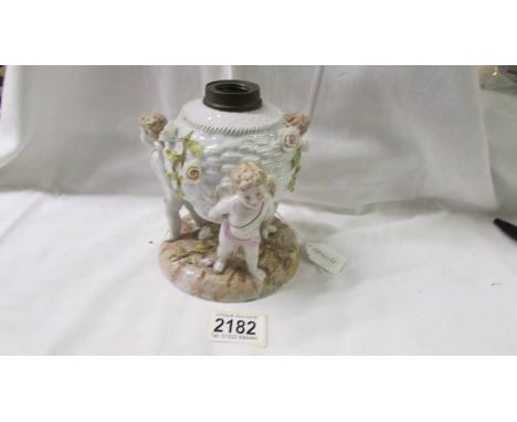 A continental porcelain cherub oil lamp base.Damage to the petal of one flower.