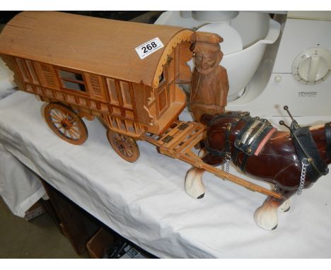 A ceramic horse with wooden cart and a carved wood figure.