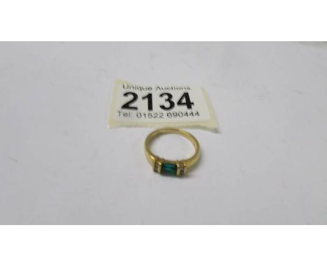 An 18ct gold ring set four diamonds and a green stone, size K half, 3.7 grams.