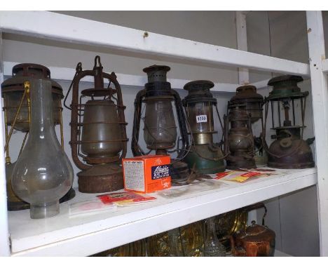 A shelf of vintage Hurricane/Tilley lamps