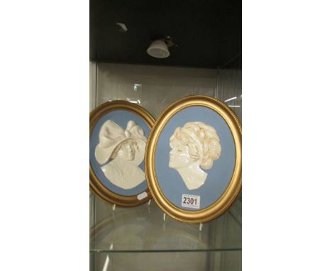 Two oval ceramic wall plaques of female heads.