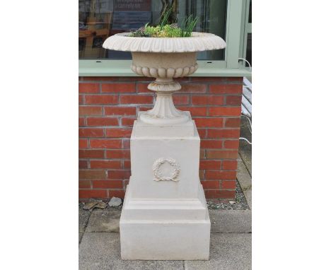 A large pair of late 19th / early 20th century cast iron campagna urns, on pedestal bases, raised on stepped square plinth ba