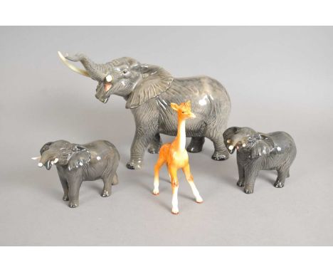 A large Beswick model of an elephant with trunk raised together with a pair of further smaller Beswick elephants and a Beswic