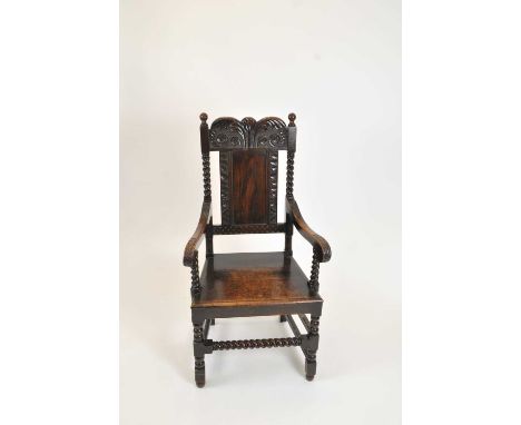 A 19th century carved oak armchair in the Carolean style, the back rail carved with symmetrical stylised trailing foliate dec