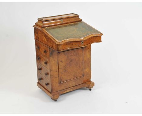 A Victorian walnut veneered Davenport, with a serpentine sloping tooled leather top before a divisional stationary box, over 