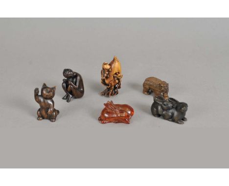 A collection of carved Japanese netsuke, to include a group of two rabbits on a large radish, a standing bear, a group of two