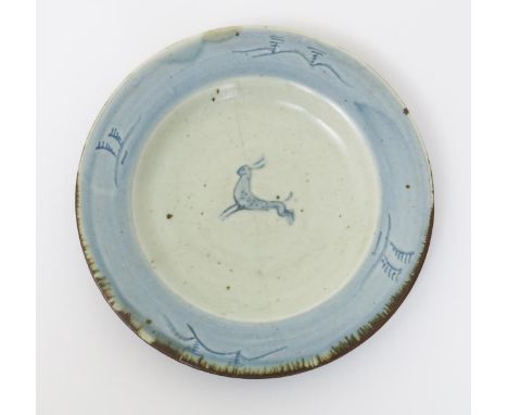 ‡ Bernard Leach (1887-1979) a Leach Pottery pottery plate, painted to the well with a hare, the rim with simple landscape mot