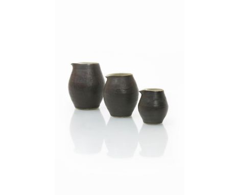 ‡ Dame Lucie Rie DBE (1902-1995) a set of three graduated stoneware pourers, glazed to the foot in manganese, the interior a 