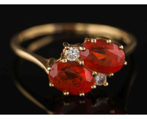 An 18ct gold, fire opal and diamond four-stone ring: the two oval fire opals between small, circular-cut diamonds, ring size 