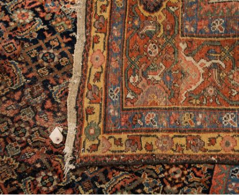 A Caucasian carpet:, the indigo field with an all over Herati design, enclosed by a main brick red geometric medallion border