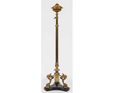 A Victorian brass standard oil lamp:, the reeded adjustable column with circular font, the shaped tripod base with mask and a
