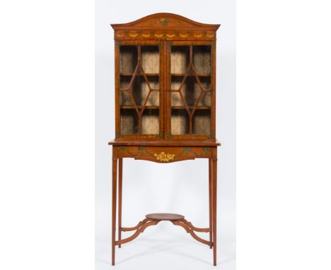 A late 19th Century satinwood and decorated display cabinet:, on serpentine fronted stand, painted with ribbon tied floral ga