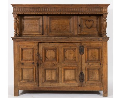 A late 17th/early 18th century oak court cupboard: the upper part with a moulded cornice and overhanging fluted and dentil fr