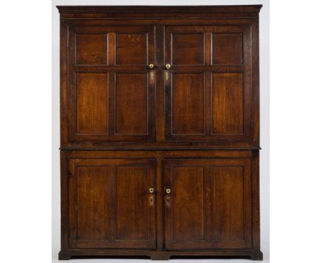 An early 19th Century oak housekeeper's cupboard:, the upper part with a moulded cornice, enclosed by a pair of moulded panel