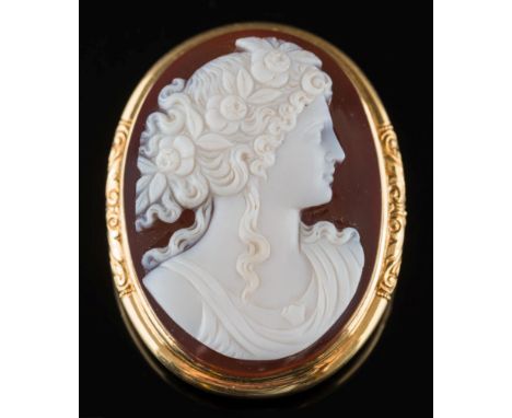 An oval hard-stone cameo portrait brooch: the oval cornelian and white agate layered cameo carved depicting the portrait of a