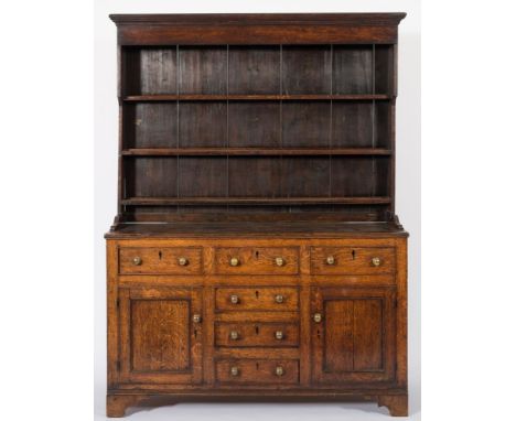 An early 19th Century oak dresser:, the shelved superstructure with a moulded cornice, the base with a reeded edge, containin