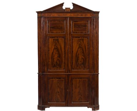 A George III mahogany and inlaid standing corner cupboard:, in two parts, having chequer feather banding, bordered with boxwo