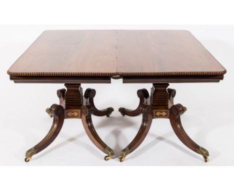 A good Regency mahogany and brass inlaid twin pillar dining table:, bordered with lines and with anthemion motif panels, the 