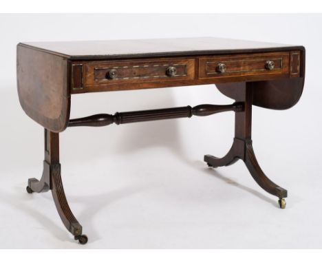 A Regency mahogany, inlaid and brass mounted sofa table:, bordered with boxwood lines, the hinged top with D -shaped leaves, 