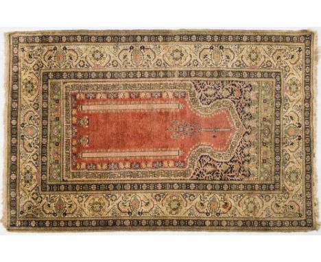 A Tabriz prayer rug:, the brick red mihrab with a hanging lantern and geometric framing with indigo ground foliate scroll des