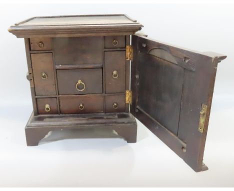 An antique oak spice cabinet with a single door opening to reveal seven small drawers, 32cm high.