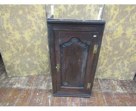 An 18th century oak wall mounted cupboard enclosed by a shaped and fielded panelled door with elm lined interior, 103cm high 