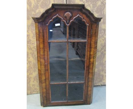 A George I style walnut hanging corner cabinet enclosed by a glazed panelled door, 118cm high x 71cm x 40cm