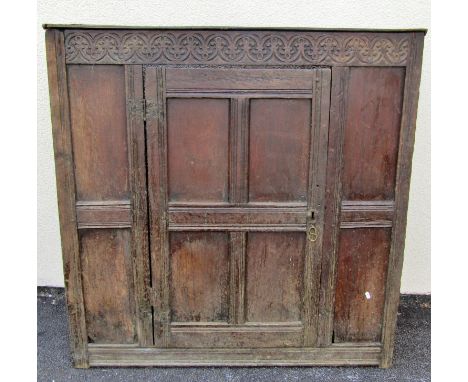 An old English oak sideboard, with shallow carved frieze above a single hinged panelled door with fluted borders (lacking she