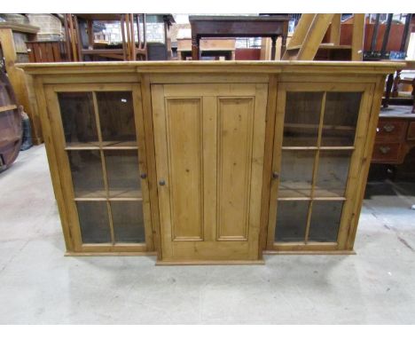 A 19th century stripped and waxed pine breakfront cabinet, the central door flanked by two glazed panelled doors, 120cm high 