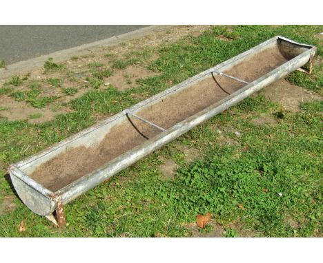 A weathered rectangular galvanised feeding trough with two simple rung divisions, later drilled and adapted as a garden plant