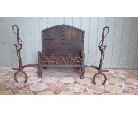 An unusual cast iron fire basket with pierced stirrup grate beneath an arched old English style back and combined dogs in the