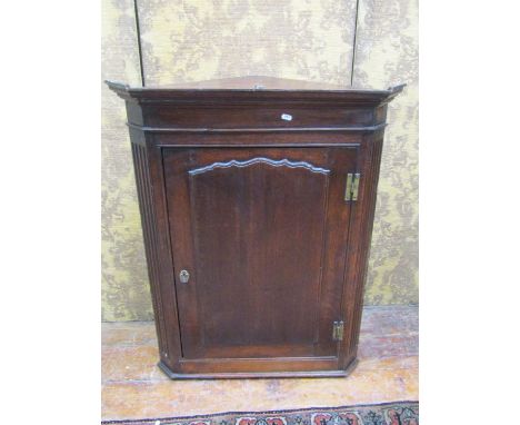 A small Georgian oak hanging corner cupboard with panelled door 